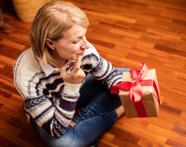 Frau sitzt auf dem Boden an einem Geschenk suchen