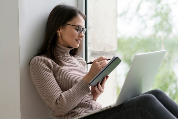 Frau sitzt auf dem Boden und arbeitet an ihrem Laptop