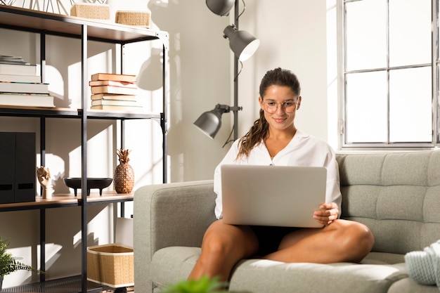 Frau sitzt auf der Couch mit Laptop