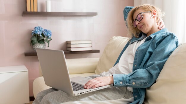 Frau sitzt auf der Couch und arbeitet am Laptop