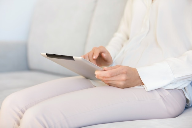 Frau sitzt auf der Couch und benutzt Tablette