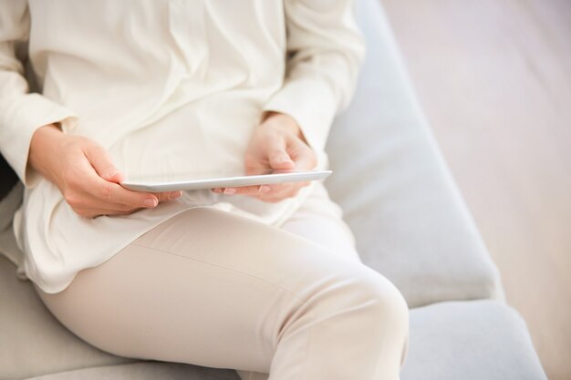 Frau sitzt auf der Couch und benutzt Tablette