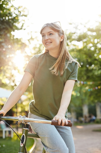 Frau sitzt auf einem Fahrrad. Porträt der jungen Frau im Stadtpark, der ein Fahrrad reitet