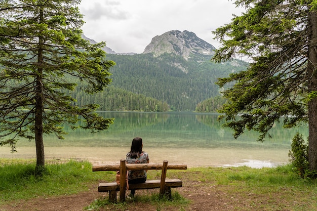 Frau sitzt auf einer Holzbank im Nationalpark Durmitor, Montenegro