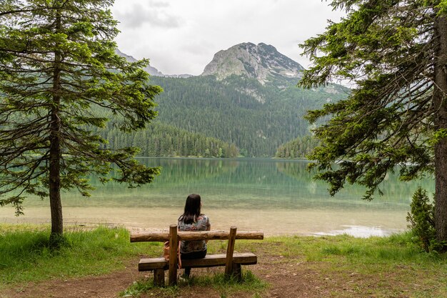 Frau sitzt auf einer Holzbank im Nationalpark Durmitor, Montenegro