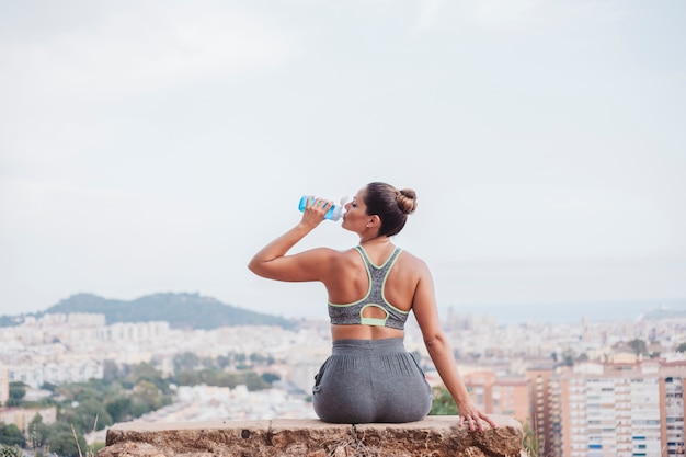 Frau sitzt auf Felsen trinken