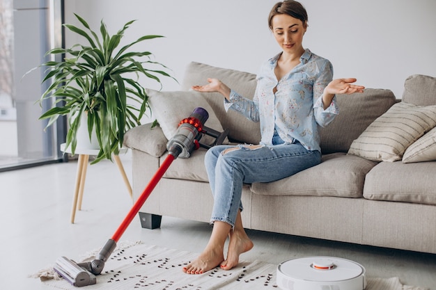 Frau sitzt auf Sofa und wählt Staubsauger vacuum