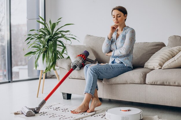 Frau sitzt auf Sofa und wählt Staubsauger vacuum