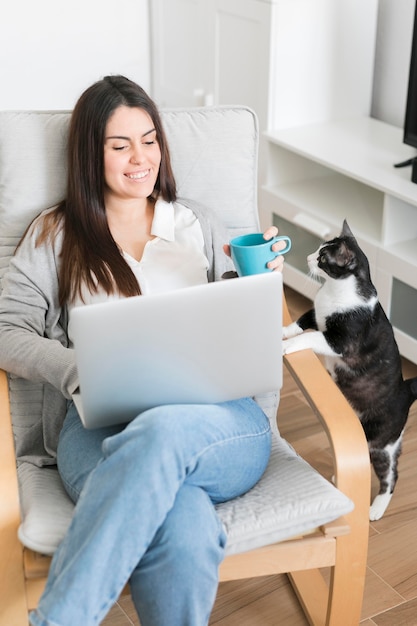 Frau sitzt auf Stuhl und arbeitet am Laptop