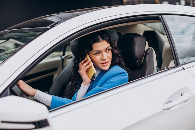 Frau sitzt im Auto und benutzt Handy