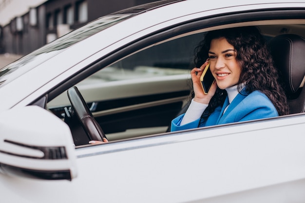 Frau sitzt im Auto und benutzt Handy