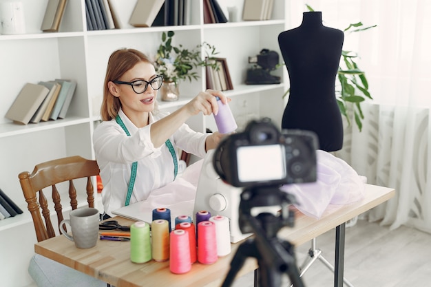 Frau sitzt im Studio und näht Stoff