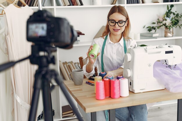 Frau sitzt im Studio und näht Stoff