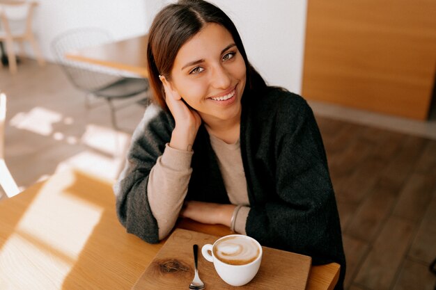 Frau sitzt in einem Café und trinkt eine Kaffeetasse