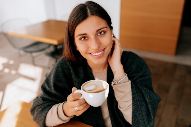 Frau sitzt in einem Café und trinkt eine Kaffeetasse