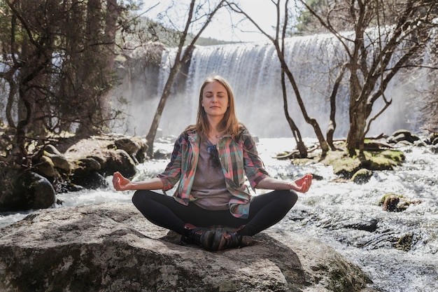 Frau sitzt in Yoga-Haltung im Freien