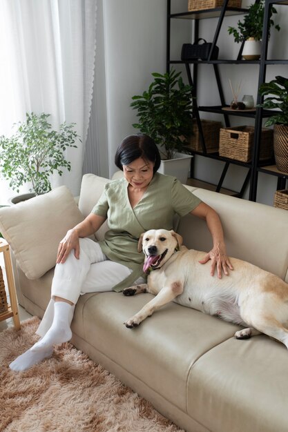 Frau sitzt mit ihrem Hund zu Hause auf dem Sofa