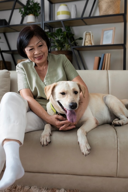 Frau sitzt mit ihrem Hund zu Hause auf dem Sofa