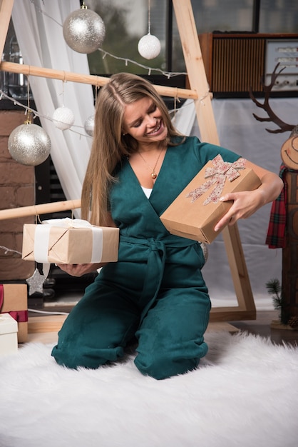 Frau sitzt zu Hause mit Weihnachtsgeschenken auf dem Boden