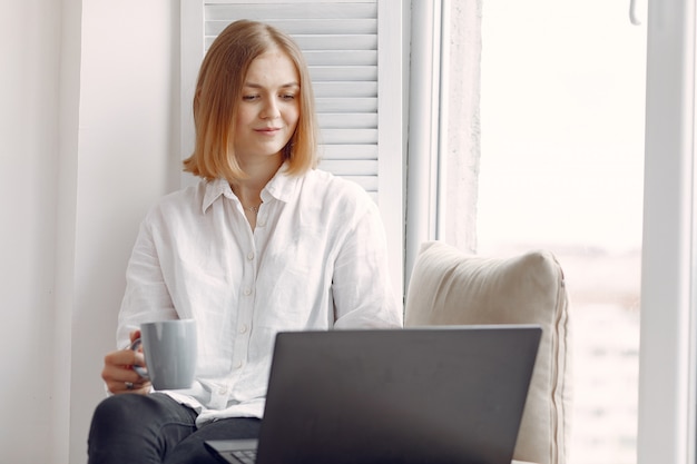 Frau sitzt zu Hause und benutzt einen Laptop