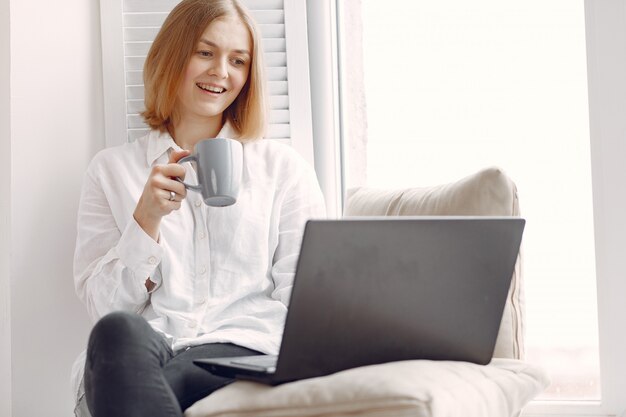 Frau sitzt zu Hause und benutzt einen Laptop