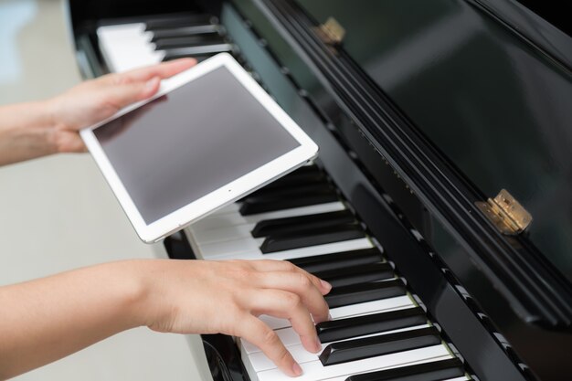 Frau spielt Klavier Hand, die eine Tablette anhält