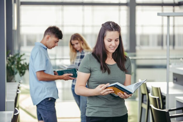 Frau stehend mit Buch in der Bibliothek