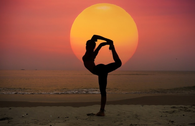 Frau stretching bein von hinten am strand