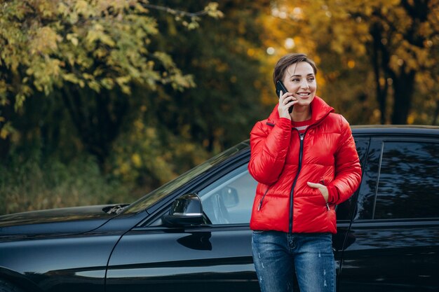 Frau telefoniert und steht an ihrem Auto