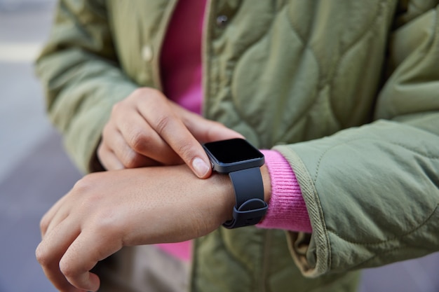Frau trägt moderne Smartwatch überprüft Ergebnisse nach dem Training zählt verbrannte Kalorien erhält Benachrichtigung auf digitaler tragbarer Armbanduhr sucht nach Zeit überwacht etwas