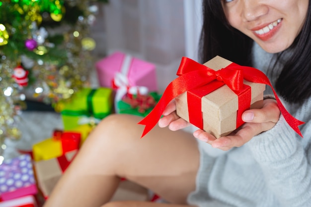 Frau trägt Weihnachtsmütze glücklich mit Weihnachtsgeschenk