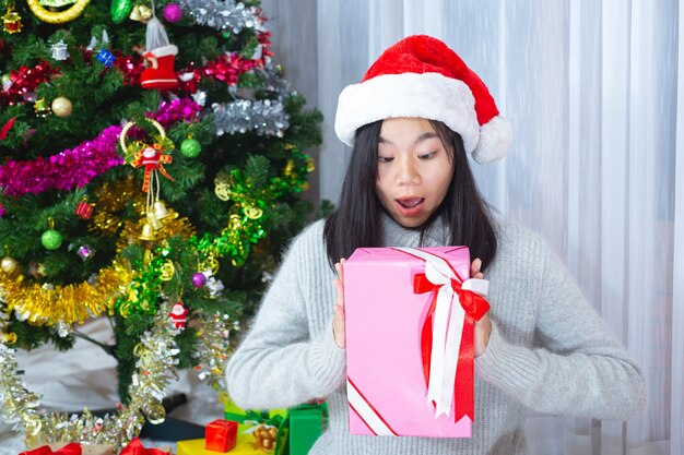 Frau trägt Weihnachtsmütze glücklich mit Weihnachtsgeschenk