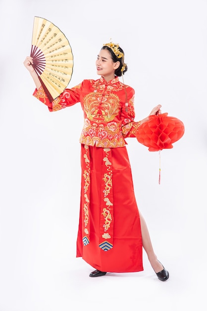Frau tragen Cheongsam Anzug fördern den chinesischen Handfächer und die rote Lampe auf großem Ereignis im chinesischen neuen Jahr