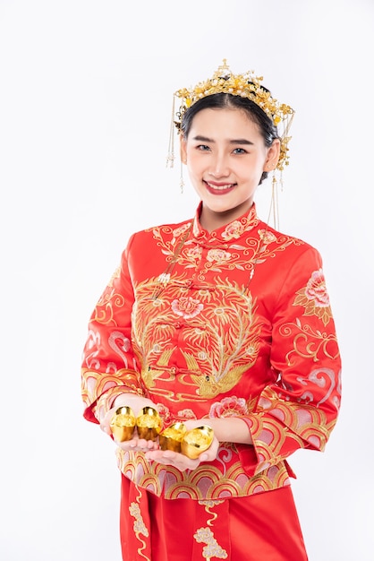 Frau tragen Cheongsam Anzug geben ihrer Familie Gold für Glück im chinesischen Neujahr