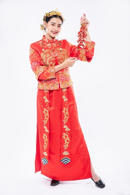 Frau tragen Cheongsam Anzug Lächeln, um Feuerwerkskörper von Verwandten im chinesischen Neujahr zu bekommen