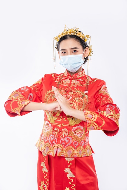 Frau tragen Cheongsam Anzug und Maske begrüßen Kunden, um im chinesischen neuen Jahr einzukaufen