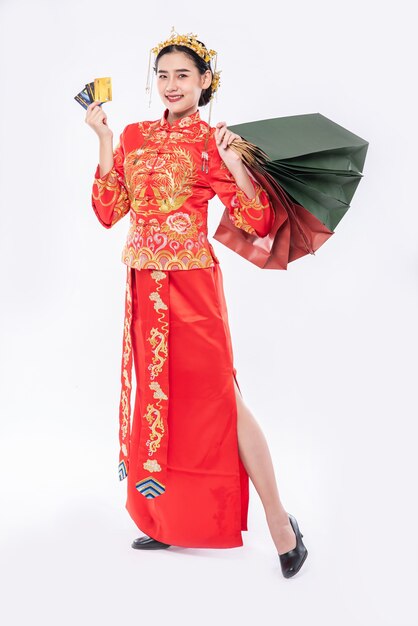 Frau tragen Cheongsam Anzuglächeln, um Kreditkarteneinkauf im chinesischen Neujahr zu verwenden