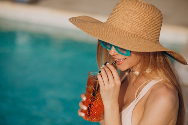 Frau trinkt Alkoholcocktail am Pool