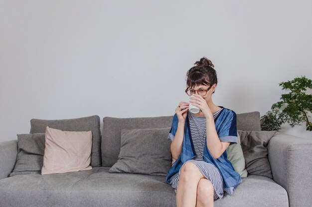 Frau trinkt Kaffee auf Sofa