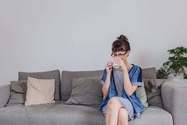 Frau trinkt Kaffee auf Sofa