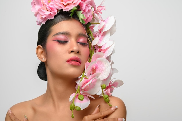 Frau trug rosa Make-up und verzierte wunderschön die Blumen isoliert auf Weiß