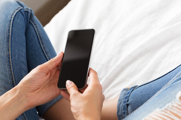 Frau überprüft das Handy auf dem Bett