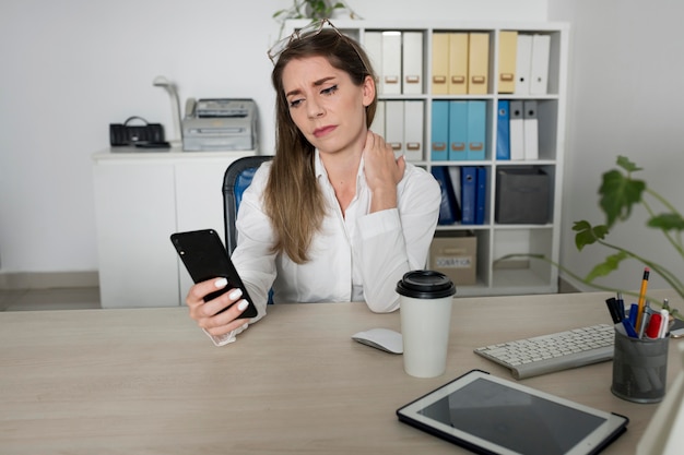 Frau überprüft ihr Smartphone bei der Arbeit