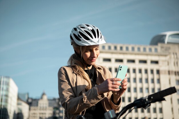 Frau überprüft ihr Smartphone und sitzt auf ihrem Fahrrad