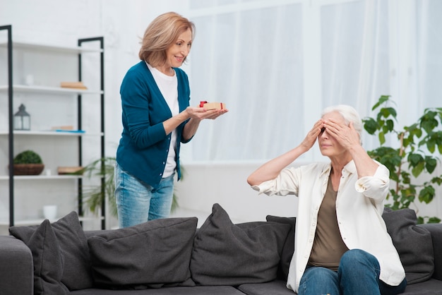 Frau überrascht ihre freundin mit einem geschenk