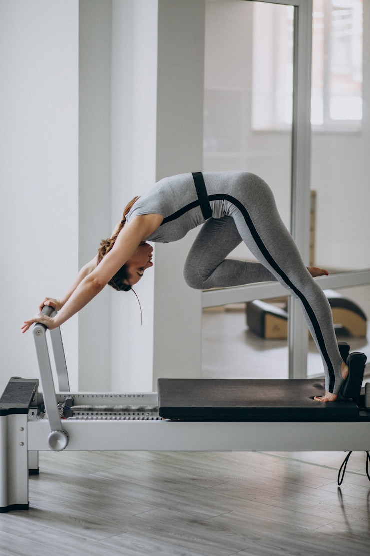 Kostenlose Foto frau übt pilates in einem pilates-reformer