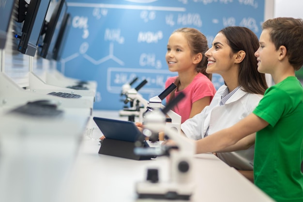 Kostenloses Foto frau und kinder seitlich zur kamera, die auf den bildschirm schauen