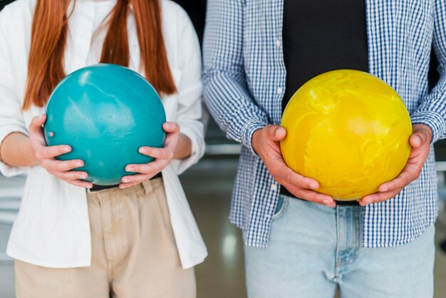 Frau und Mann, die bunte Bowlingspielkugeln anhalten