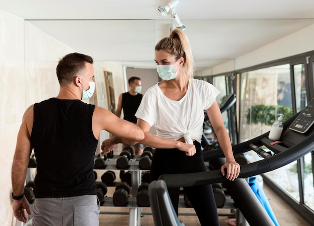 Frau und Mann, die Ellbogen benutzen, um sich im Fitnessstudio zu grüßen