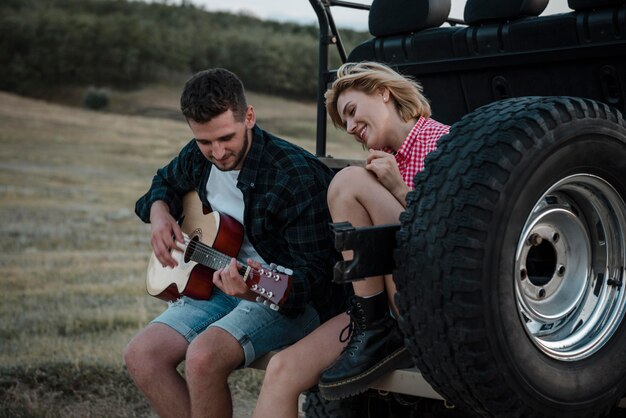 Frau und Mann, die Gitarre spielen, während sie mit dem Auto reisen